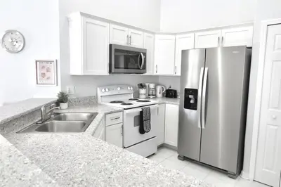 a kitchen with white cabinets and a stainless steel refrigerator at 7832 Cozy Gem at Indian Ridge with Pool in Orlando