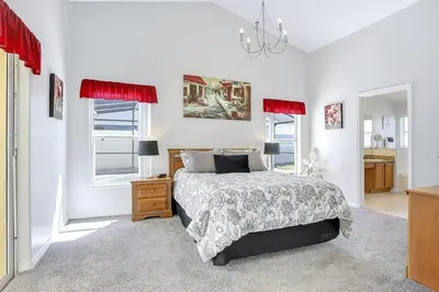 a bedroom with a bed and a dresser and two windows at 7832 Cozy Gem at Indian Ridge with Pool in Orlando