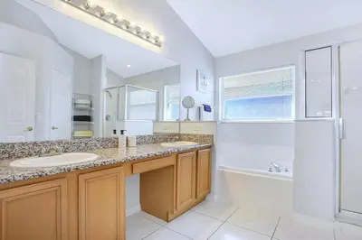 a white bathroom with two sinks and a shower at 7832 Cozy Gem at Indian Ridge with Pool in Orlando