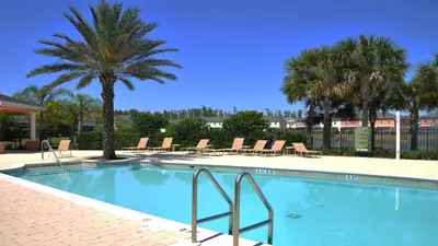 a swimming pool with chairs and palm trees at Shvck3 - Coral Cay Resort #3 - 4 Bed 3 Baths Townhome in Kissimmee