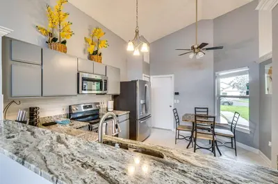 a kitchen with white cabinets and a table with chairs at Lovely Florida Retreat with Lanai 5 Mi to Riverwalk in Lake Mary