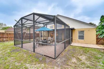 an enclosed patio with a table and an umbrella at Lovely Florida Retreat with Lanai 5 Mi to Riverwalk in Lake Mary