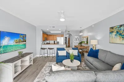 a living room with a gray couch and blue chairs at Scenic View Condo Near Disney in Orlando