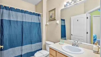 a bathroom with a blue shower curtain and a sink at Shvck5 - Coral Cay Resort #5 - 4 Bed 3 Baths Townhome in Kissimmee