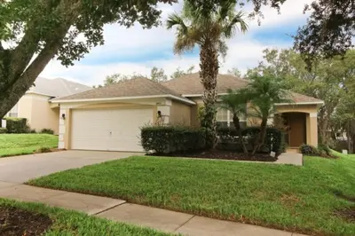 a house with a garage and palm trees at Gorgeous 4 Bed Home In Gated Community! villa in Kissimmee
