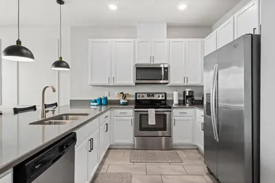 a kitchen with white cabinets and a stainless steel refrigerator at Charming Challet at Compass Bay CB101 in Kissimmee