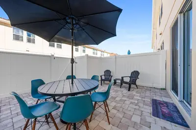 a table with chairs and an umbrella on a patio at Charming Challet at Compass Bay CB101 in Kissimmee