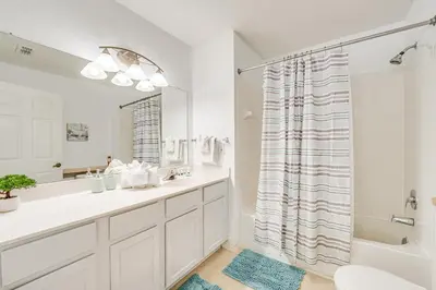 a white bathroom with a tub and a sink at 11 Mi to Disney Venetian Bay Villages Townhome! in Kissimmee
