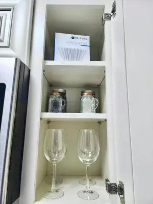 two wine glasses and a box in a cabinet at Happy Place in Orlando