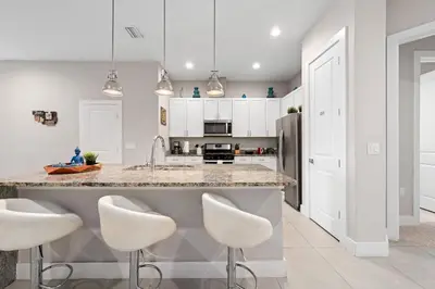 a kitchen with white cabinets and white stools at 4 Bedrooms 3 En-Suites, 5 Min to Disney SMV158 in Orlando