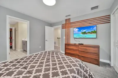 a bedroom with a bed and a tv on a wall at 9 BR Family Home 8 Minutes to Disney STL119 in Kissimmee