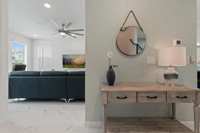 a living room with a blue couch and a mirror at Stunning Modern Home VPR102 in Kissimmee