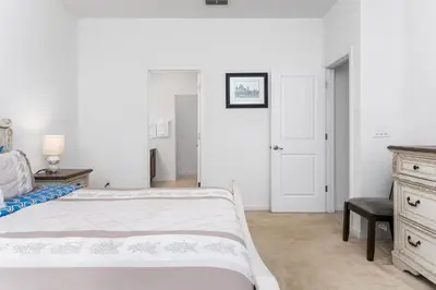 a white bedroom with a bed and a chair at Lakeview Home Sleeps 25 VPR103 in Kissimmee