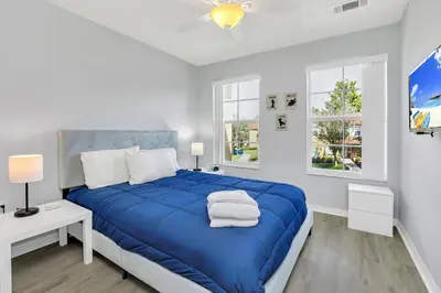 a white bedroom with a blue bed and two windows at A Peaceful Orlando Escape, nature, comfort & Disney Nearby EMI101 in Kissimmee
