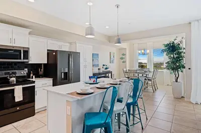 a kitchen with white cabinets and a table with blue chairs at 3141 Paradox Circle 406 in Kissimmee