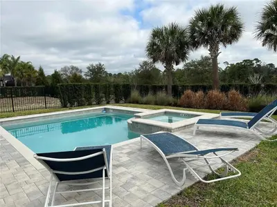a swimming pool with two lawn chairs and a pair at 7491 Oasis at Reunion sleeps 12 in Orlando