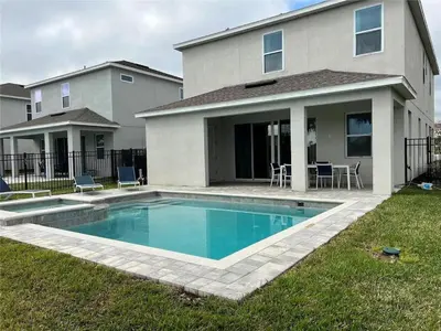 a house with a swimming pool in front of a house at 7491 Oasis at Reunion sleeps 12 in Orlando