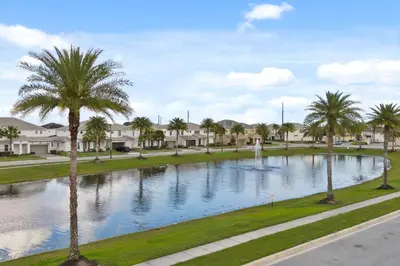 a large pond with palm trees and houses at Brand New Masterpiece 15 En-Suites SON105 in Kissimmee