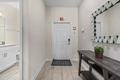 a hallway with a white door and a table at Comfy Townhome 8 Min to Disney STL120 in Kissimmee