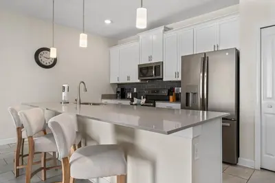 a kitchen with white cabinets and a stainless steel refrigerator at Comfy Townhome 8 Min to Disney STL120 in Kissimmee