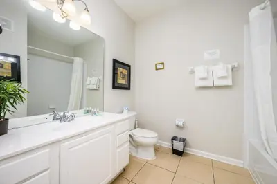 a bathroom with a toilet and a sink and a mirror at Epic Universe Premium Lake View Condo, Vista Cay - 1002 in Orlando