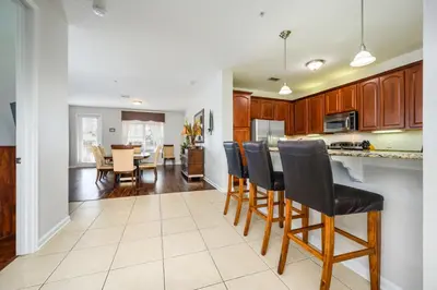a kitchen with wooden cabinets and a table with chairs at Epic Universe Premium Lake View Condo, Vista Cay - 1002 in Orlando