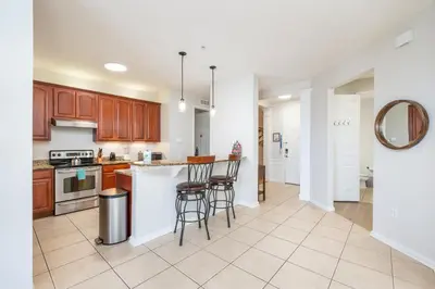 a kitchen with wooden cabinets and bar stools at Beautiful Lakeview Condo, New Listing -1024 in Orlando
