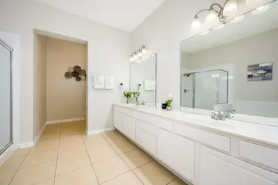 a white bathroom with two sinks and a large mirror at Epic Universe Penthouse Vacation Condo, Near The Parks - 2014 in Orlando
