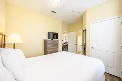 a bedroom with a white bed and a television at Beautiful Deluxe Condo, Vista Cay - 3015 in Orlando