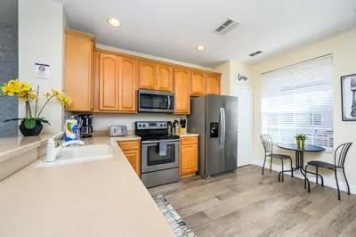 a kitchen with stainless steel appliances and a table at Epic Universe Beautiful Vacation Townhome - 4031 in Orlando