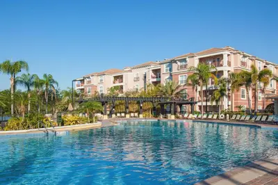 a large swimming pool with palm trees and buildings at Top Floor Modern Vista Cay Reserve Condo - 5004 in Orlando