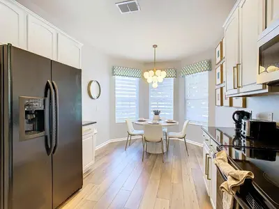a kitchen with a table and a stainless steel refrigerator at WH7820BS - 5 bedrooms - Pool - Theater - Resort in Orlando