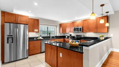 a kitchen with wooden cabinets and a stainless steel refrigerator at Ultimate Summer Retreat - TownHome by Disney! in Orlando