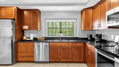 a kitchen with wooden cabinets and a sink at Sunny Summer in Orlando - TownHome by Disney! in Orlando