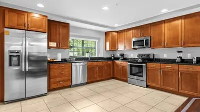 a kitchen with wooden cabinets and stainless steel appliances at Sunny Summer in Orlando - TownHome by Disney! in Orlando