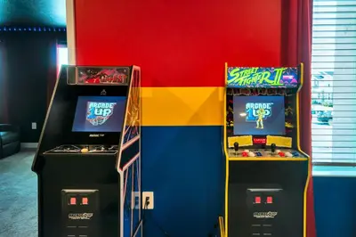 two arcade video games in front of a colorful wall at Magical Mickey Home 8 minutes from Disney STL109 in Kissimmee
