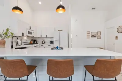a kitchen with a large white counter and chairs at Indian Ridge - Pool Home with Spa, Newly Renovated in Orlando