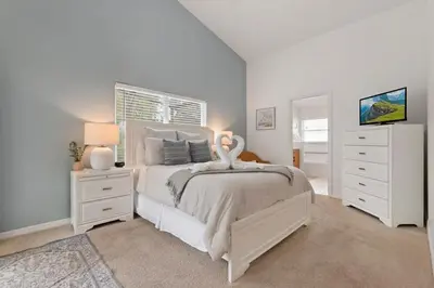 a white bedroom with a bed and a tv at Indian Ridge - Pool Home with Spa, Newly Renovated in Orlando