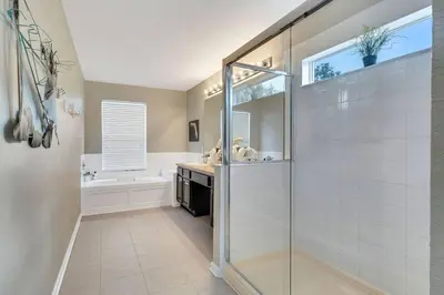a bathroom with a shower and a sink and a tub at Immersive Themed Villa in Resort 4mi to Disney with Game Room and Private Pool in Orlando