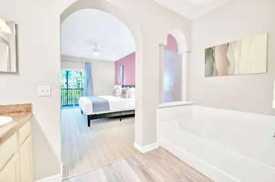 a bathroom with a tub and a bedroom with a bed at Modern 3BR Condo Near Disney- Pool in Orlando