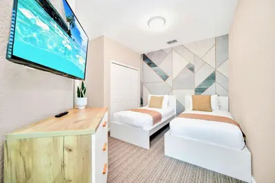 a room with two beds and a flat screen tv at Modern 3BR Condo Near Disney- Pool in Orlando