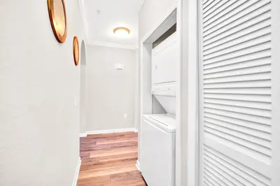 a walk in closet with white walls and wood floors at Modern 3BR Condo Near Disney- Pool in Orlando