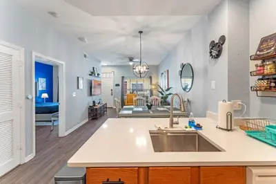 a kitchen with a sink and a living room at Mickey's Magical Townhome Venetian Bay Villages in Kissimmee