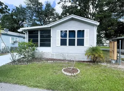 a white house with a window in a yard at Sherwood Forest Mobile Home in Kissimmee