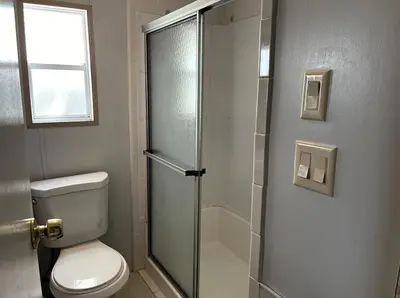 a bathroom with a toilet and a glass shower door at Sherwood Forest Mobile Home in Kissimmee
