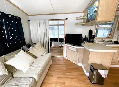 a living room with a couch and a kitchen at Sherwood Forest Mobile Home in Kissimmee