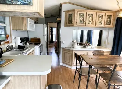 a kitchen with wooden cabinets and a table with chairs at Sherwood Forest Mobile Home in Kissimmee