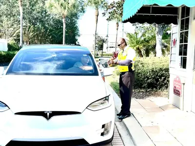 a man is standing next to a white car at The Villas at Seven Dwarfs - 2624 Mickey Villa - Near Disney - Water Park in Kissimmee