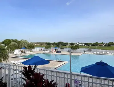 a large swimming pool with blue umbrellas in a resort at Stunning Ventura Condo in Orlando
