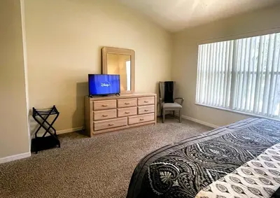 a bedroom with a bed and a dresser with a mirror at Ventura Village Cottage Grove Townhome in Orlando